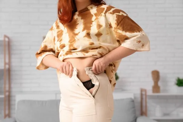 Image of woman trying to do her trousers up after pregnancy weight gain Winslow