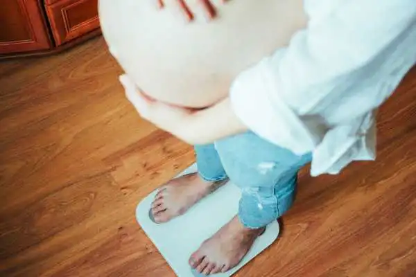 Image of woman weighing herself and experiencing weight gain through pregnancy Winslow